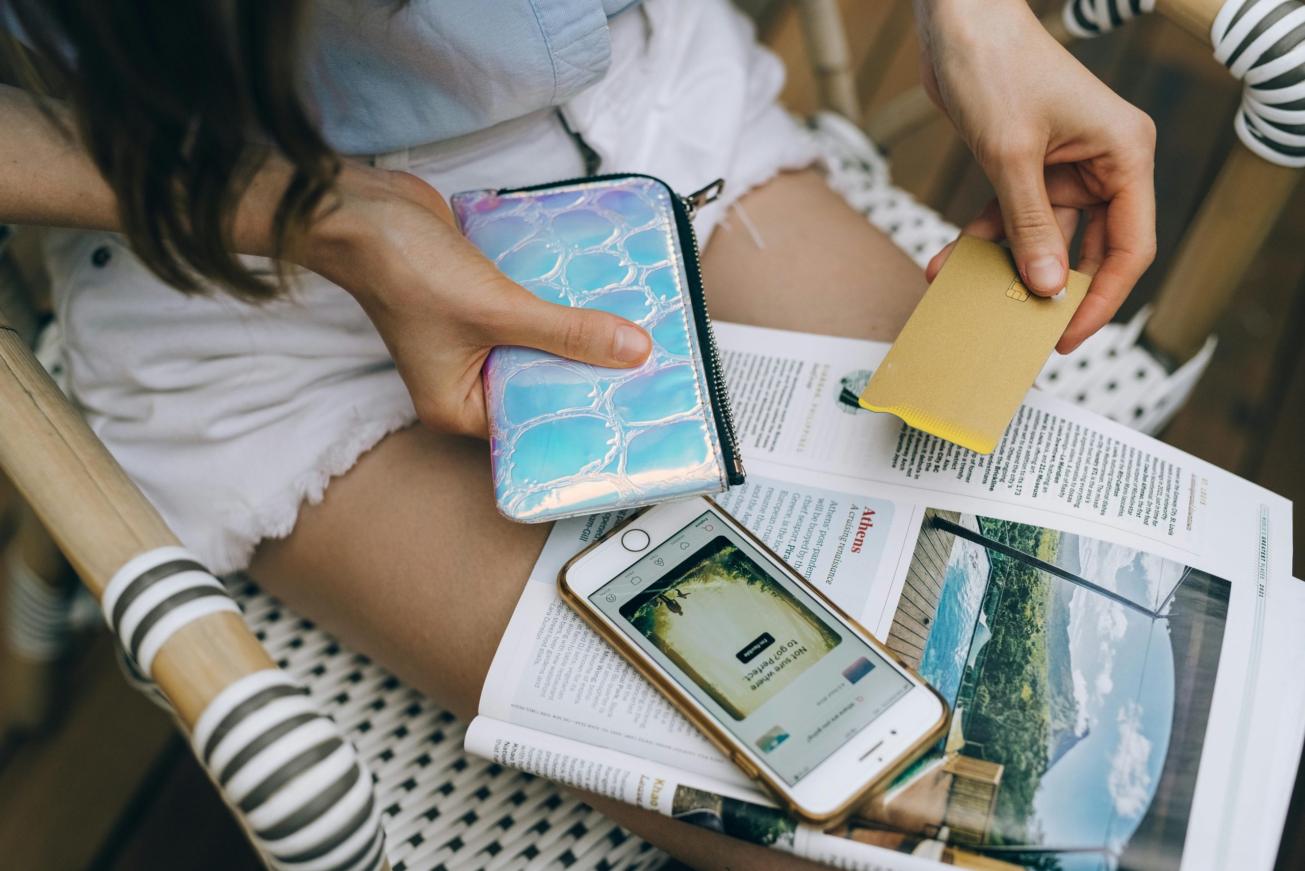 A woman uses her smartphone and credit card for online shopping while sitting outdoors.