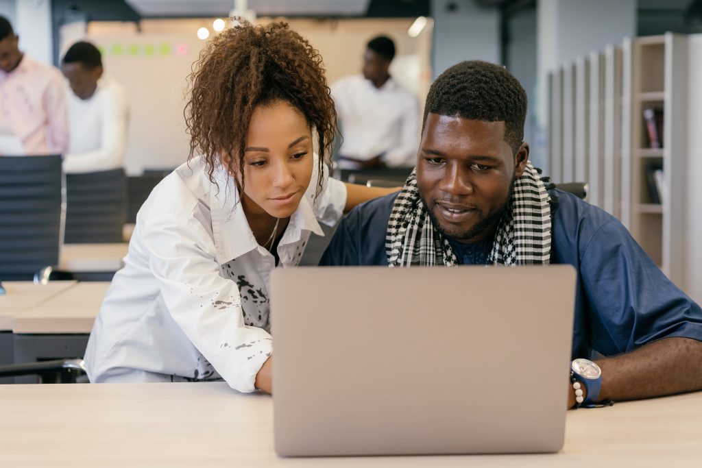 Two colleagues working together on a laptop in a contemporary office environment.